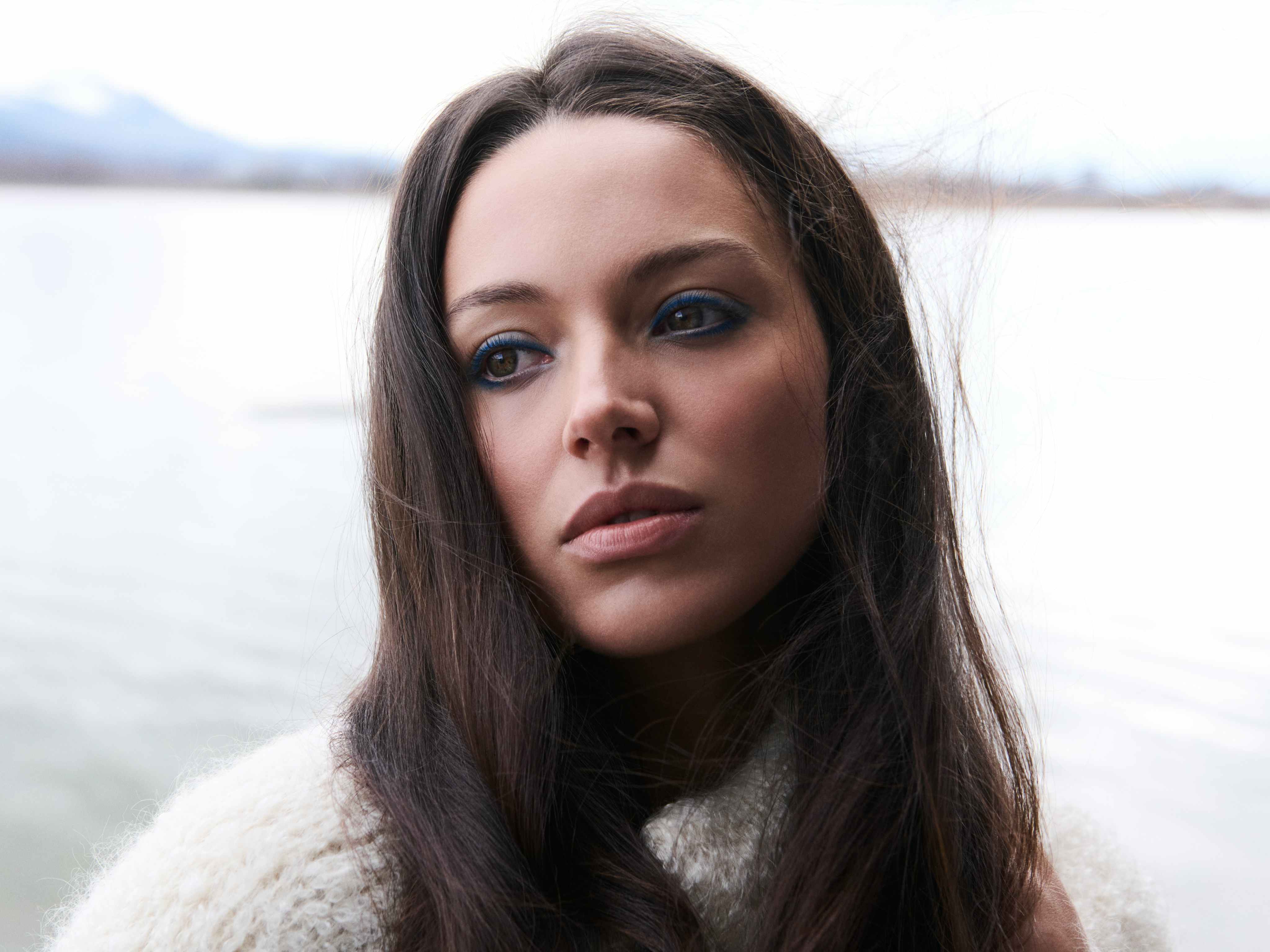 Woman with long brown hair against a water landscape