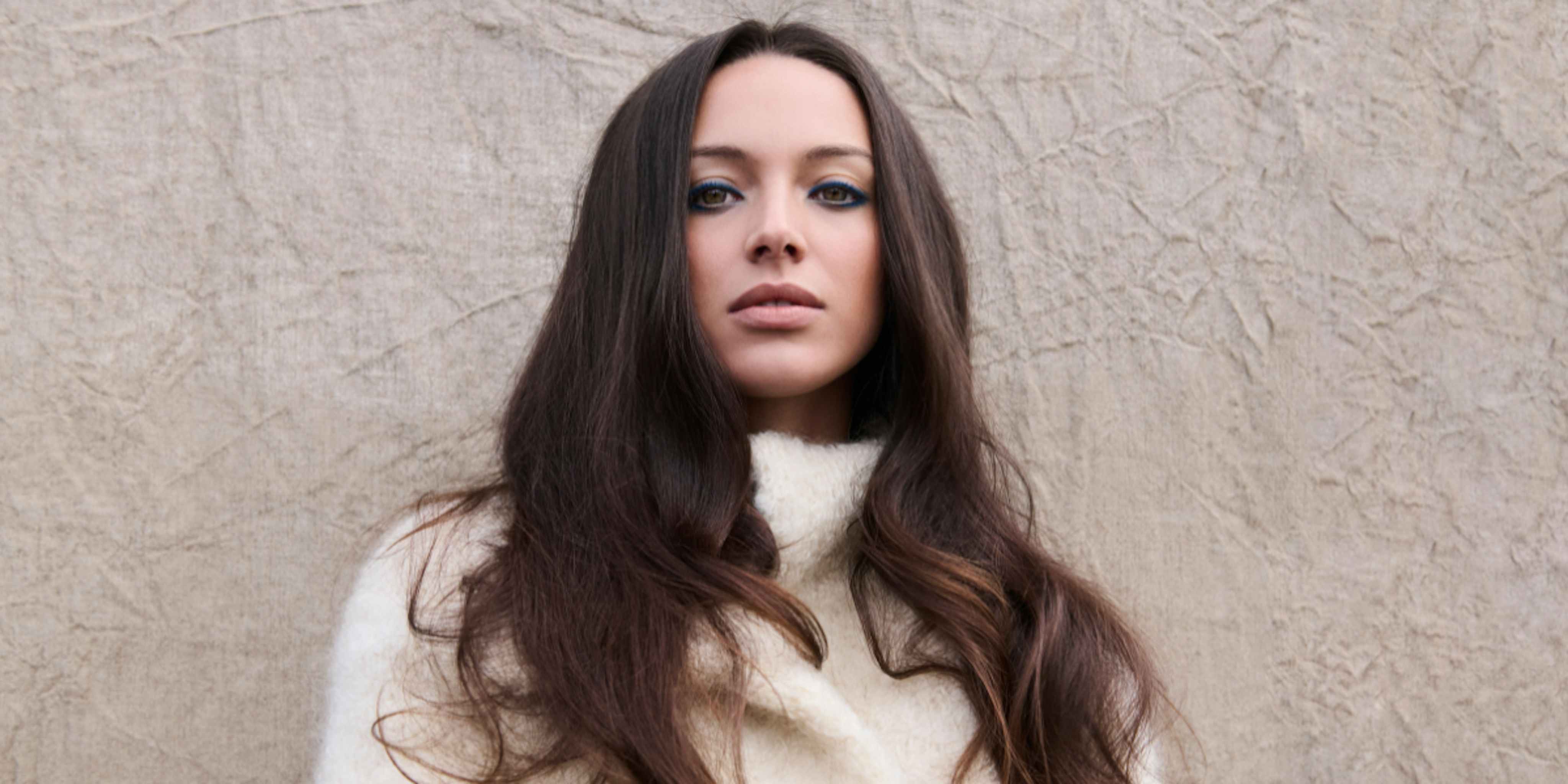 Woman with long dark hair in a white sweater